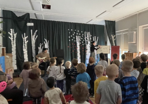 Pani pokazuje książki a dzieci stoją i przyglądają się