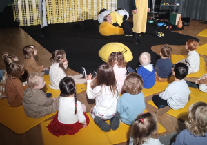 Dzieci siedzą i słuchają co opowiada aktorka.