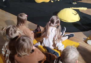 Dzieci siedzą i słuchają co opowiada aktorka.