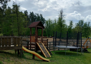 Sprzęt do zabawy dla dzieci, zjeżdżalnie i trampolina na polanie.
